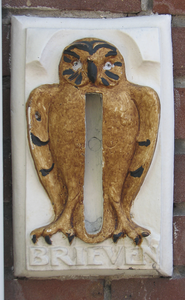 908477 Afbeelding van een staande dichtgezette en overgeschilderde keramieken brievenbus met de vorm van een uil, naast ...